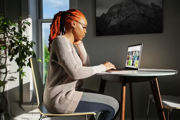 Woman trading online from a laptop at a sunlit table